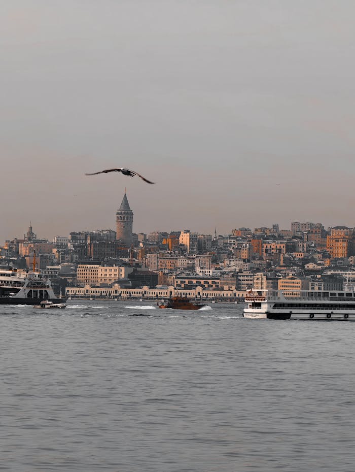 hero-img-02 Scenic view of Istanbul skyline with iconic Galata Tower and boats on the water at sunset.